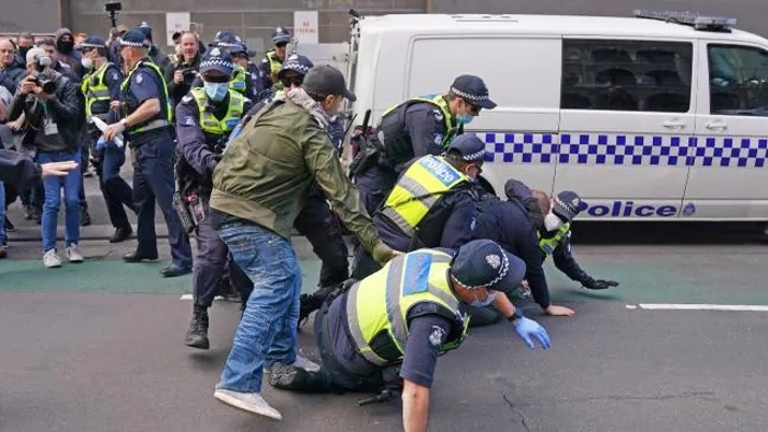 Police officers detain a man outside Parliament House in Victoria. (Photo / AAP)
