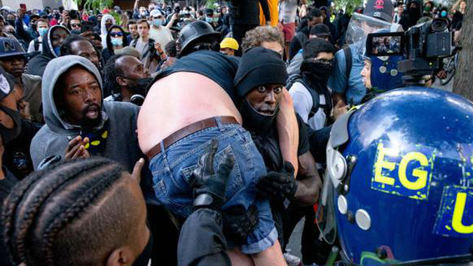 A group of men carry an injured man away after he was allegedly attacked by some of the crowd of protesters. Photo / Getty Images