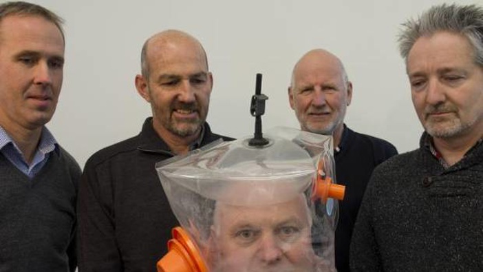 Mark Seaton, Chris Hopkins, William Early and Andrew Wallace look on as Richard Aimers tries on a ventilator hood made in Dunedin. Photo / ODT