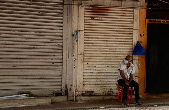 An elderly man wearing a mask to curb the spread of the new coronavirus, sits outside a closed grocery shop in downtown Panama City. (Photo / Supplied)