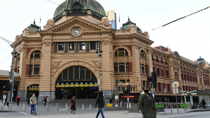 People wearing face masks cross the road outside Flinders Street Station in Melbourne. (Photo / AAP)