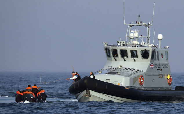 A Border Force vessel assist a group of people thought to be migrants on board from their inflatable dinghy in the Channel. (Photo / AP)