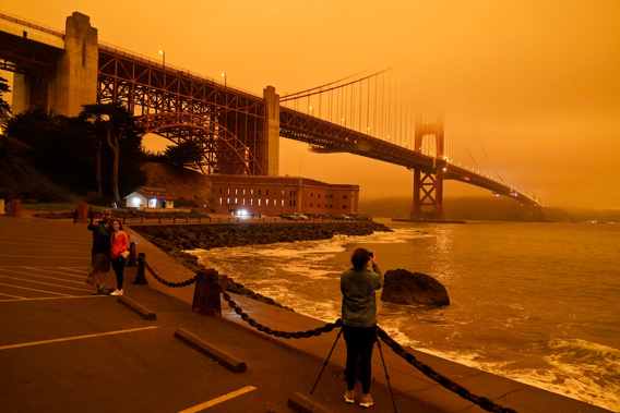 People at Fort Point in San Francisco take pictures of the Golden Gate Bridge obscured by smoke. PHOTO: Eric Risberg/AP