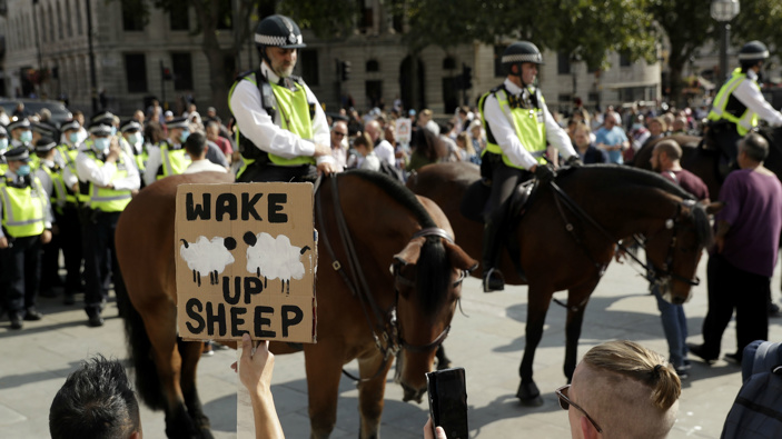 A protester holds up a placard in front of police officers during a "Resist and Act for Freedom" protest against a mandatory coronavirus vaccine. (Photo / AP)