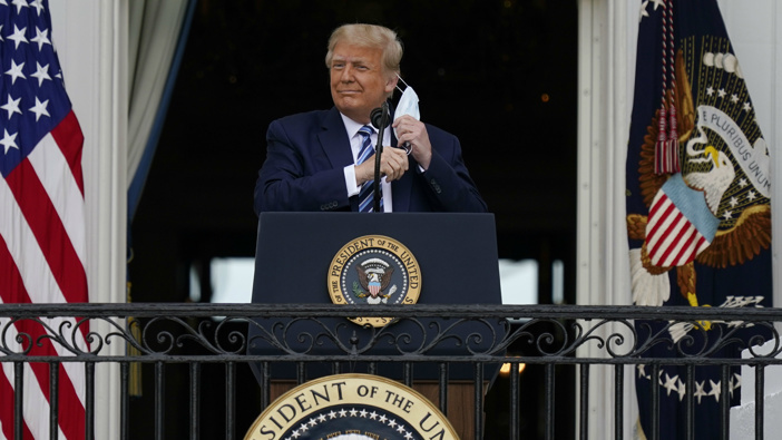President Donald Trump removes his face mask to speak from the Blue Room Balcony of the White House to a crowd of supporters. (Photo / AP)