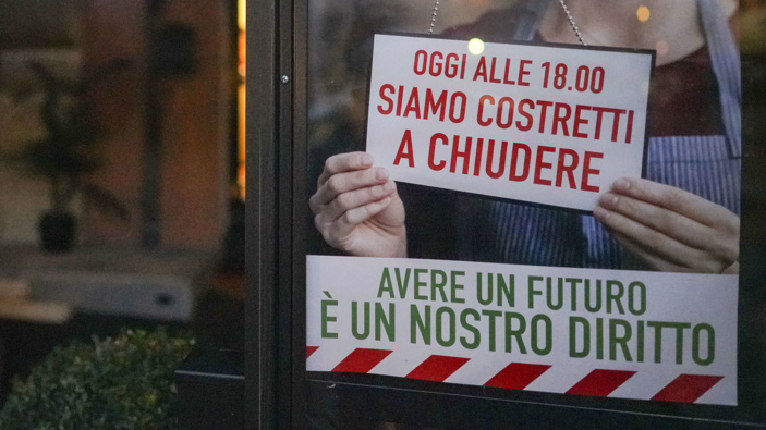A notice reading "today we are forced to close at 18.00, to have a future is our right" hangs on the door of a restaurant, in downtown Rome,