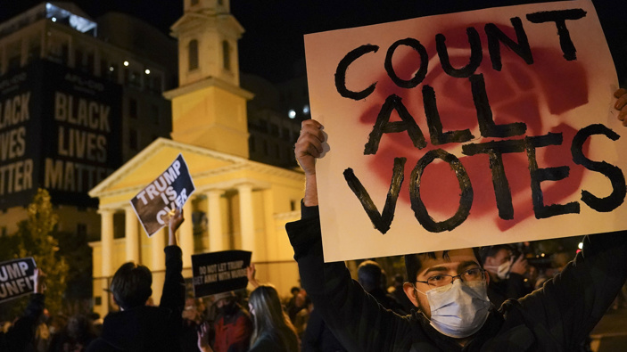A demonstrator holds up a sign while waiting for election results at Black Lives Matter Plaza in Washington. (Photo / AP)