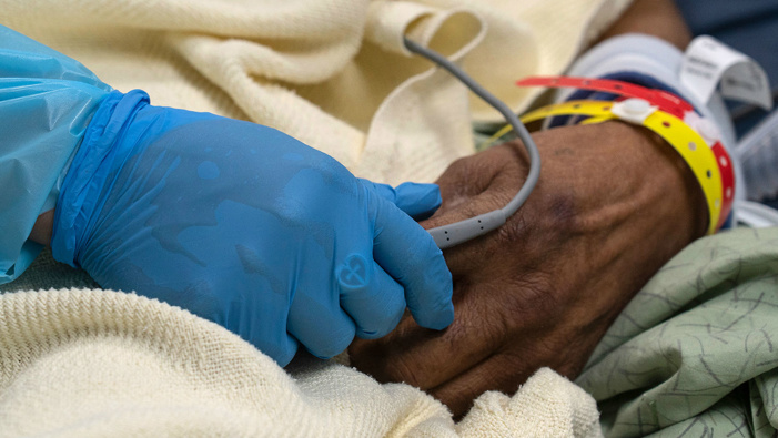 A medical staff member holds a hand of a patient suffering from COVID-19 in the COVID-19 intensive care unit (Photo / Getty)