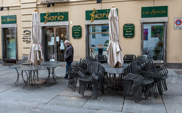 A man wearing a face mask to curb the spread of the new coronavirus walks past a closed cafe, in Turin, northern Italy on Nov. 6.