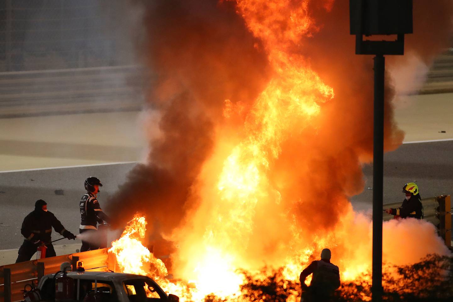 Staff extinguish flames from Haas driver Romain Grosjean's car during the Formula One race in Bahrain. Photo / AP
