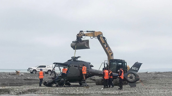 The wreckage of the helicopter is removed from Kēkerengū Beach. Photo / Anna Leask