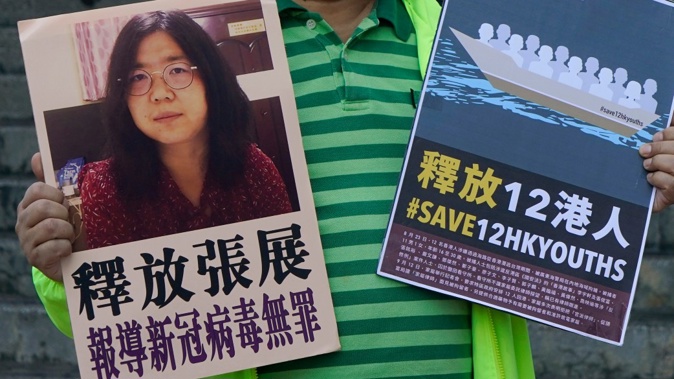 A pro-democracy activist holds placards with the picture of Chinese citizen journalist Zhang Zhan outside the Chinese central government's liaison office, in Hong Kong. (Photo / AP)