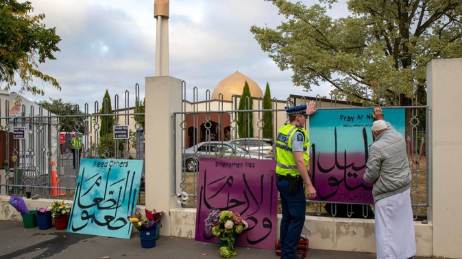 A police officer helping to attach messages to the fence at Al Noor mosque in Christchurch on the first anniversary of the terror attacks last year. Photo / Mark Mitchell