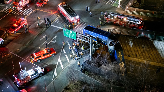 A bus in New York City which careened off a road in the Bronx neighborhood of New York is left dangling from an overpasss. (Photo / AP)