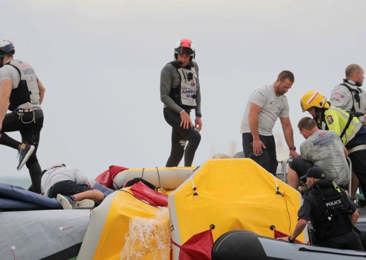 American Magic helmsman Dean Barker oversees the efforts to stop Patriot from sinking. Photo / Michael Craig