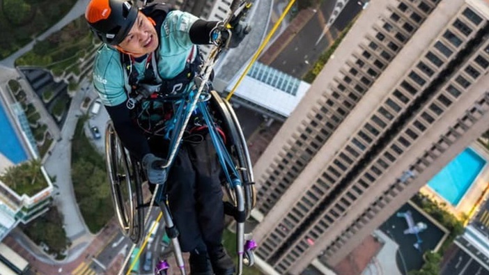 Lai Chi-wai battled the weight of a wheelchair on the way up the 320-metre-tall Nina Tower. Photo / Supplied, Ignite