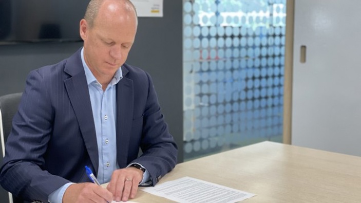MedSafe Group Manager Chris James signing the gazette notice to grant provisional approval to the vaccine. (Photo / Supplied)