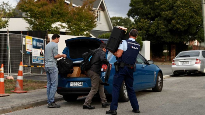 Police take computer equipment out of the house in Christchurch. Photo / George Heard