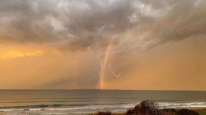 A lightning strike and rainbow in the ocean off Papamoa East. Photo / Izzy Crosson