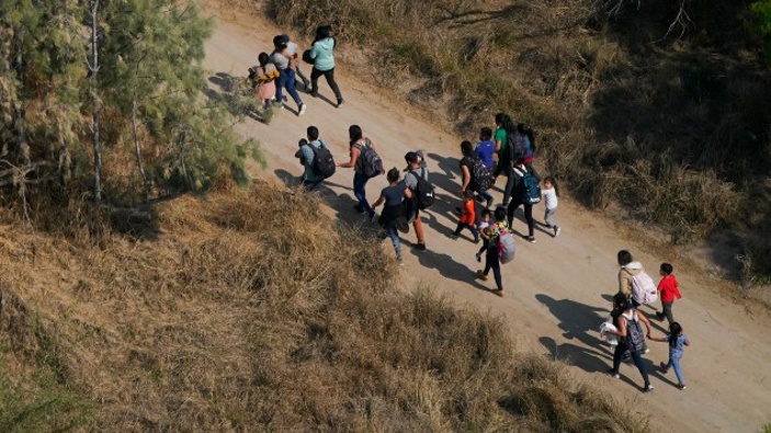 Migrants walk on a dirt road after crossing the U.S.-Mexico border, Tuesday, March 23, 2021, adnist a surge of migrants on the Southwest border has the Biden administration on the defensive. (Photo / AP)