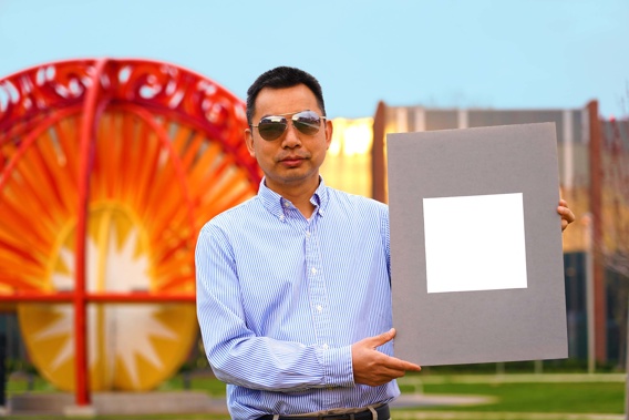 Xiulin Ruan, a Purdue University professor of mechanical engineering, poses with a sample of the new, sunlight reflecting paint.
