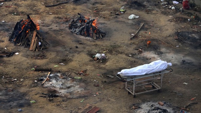 Multiple funeral pyres of those patients who died of COVID-19 disease are seen burning at a ground that has been converted into a crematorium for mass cremation of coronavirus victims, in New Delhi, India. (Photo / AP)