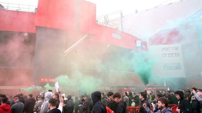 Fans make their way past barriers outside the ground as they let off flares whilst protesting against the Glazer family, owners of Manchester United, before their Premier League match against Liverpool at Old Trafford. (Photo / AP)