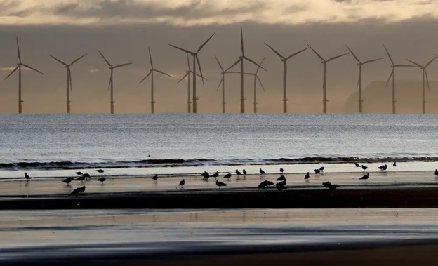 An offshore wind farm is visible from the beach in Hartlepool, England. Photo / AP