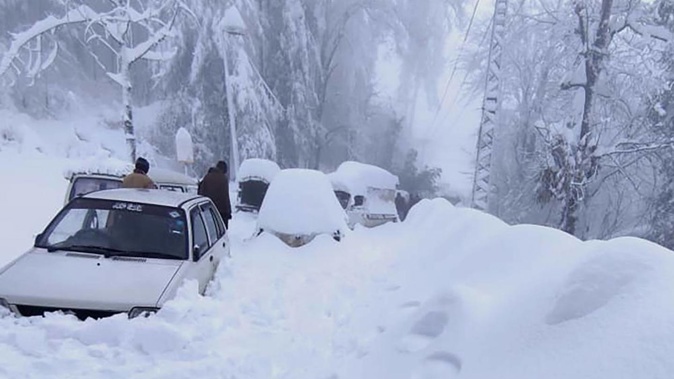 In this photo provided by the Inter Services Public Relations, people walk past vehicles trapped in a heavy snowfall-hit area in Murree. Photo / AP