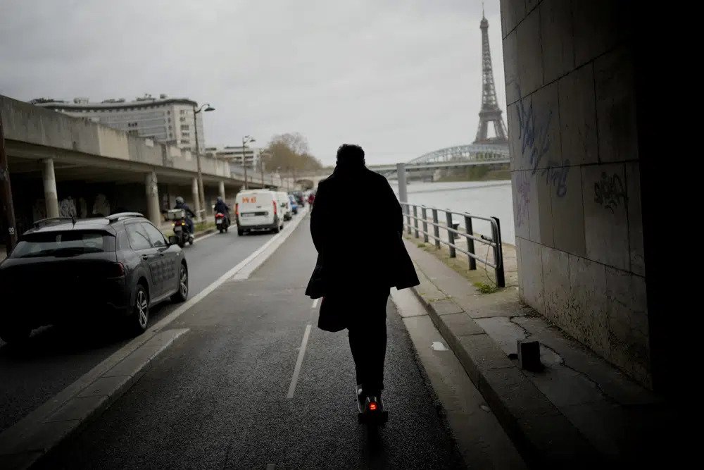 A man rides a scooter in Paris, Friday, march 31, 2023. Romantically zipping two-to-a-scooter, wind in the hair, past the Eiffel Tower and other iconic sights could soon become a thing of the past if Parisians vote Sunday to do away with the 15,000 opinion-dividing micro-machines. (AP Photo/Christophe Ena)