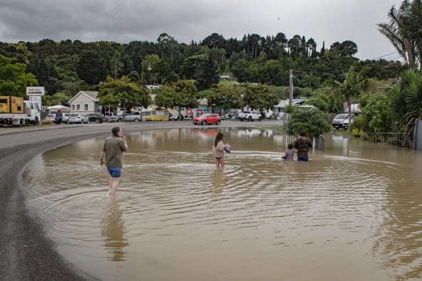 Esther Robson, Daniel Munro, River Munro, 7, and Aeris Munro, 10, wade through floodwaters in Bayview, Napier. Photo / Warren Buckland