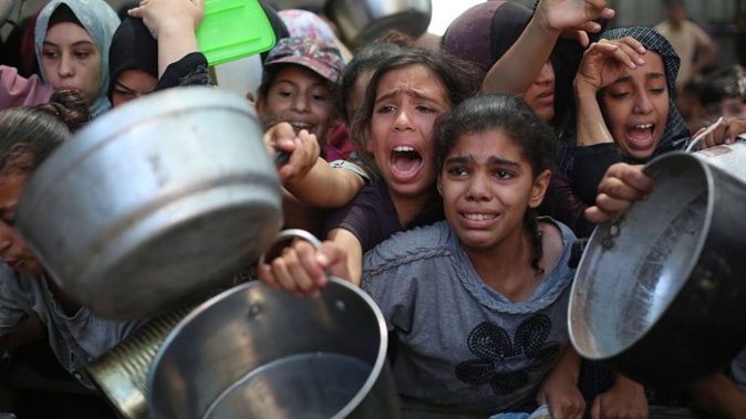 Palestinians wait to receive hot meals with their pots and pans in Deir Al Balah, Gaza. Photo / Anadolu via Getty Images