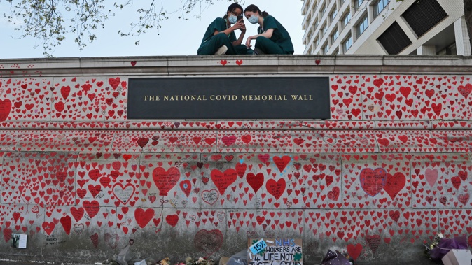 In this Tuesday, April 27, 2021 file photo, nurses from the nearby St. Thomas' hospital sit atop the National Covid Memorial Wall in London. (Photo / AP)