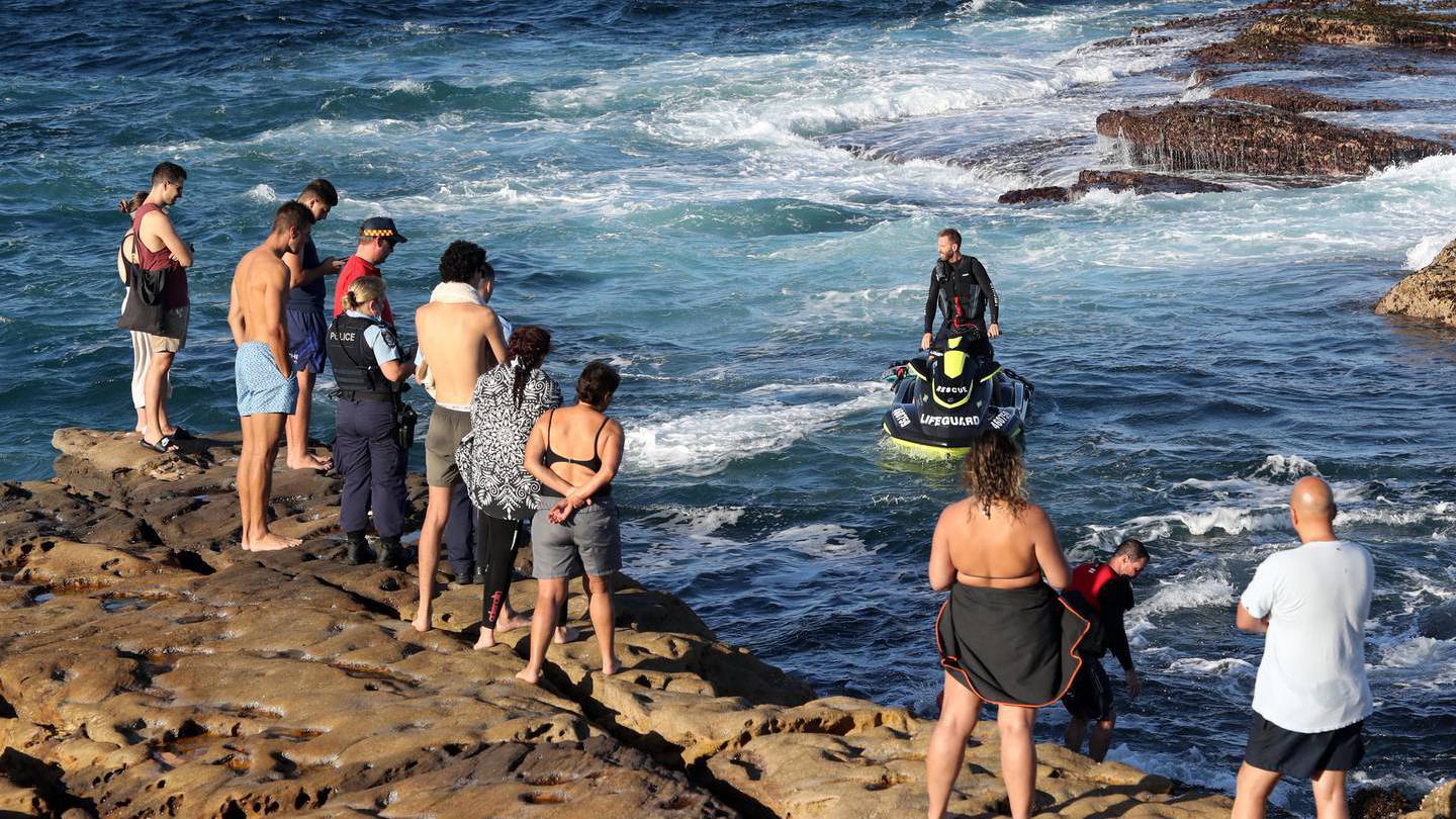 Police, surf rescue and members of the public look on at a surf rescue member after the shark attack at Little Bay, Sydney. (Photo / News Ltd)