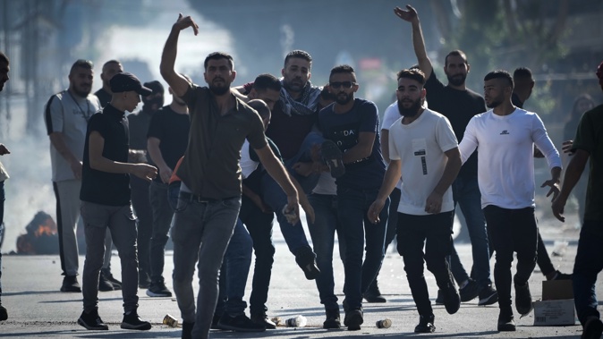 Palestinian demonstrators carry injured during clashes with Israeli forces following a demonstration in support of the Gaza Strip in the West Bank city of Nablus, Friday, Oct. 13, 2023. Photo / AP