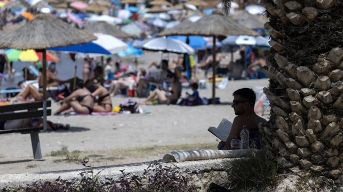 A man sits in the shade at a beach in Glyfada, Greece. Photo / AP