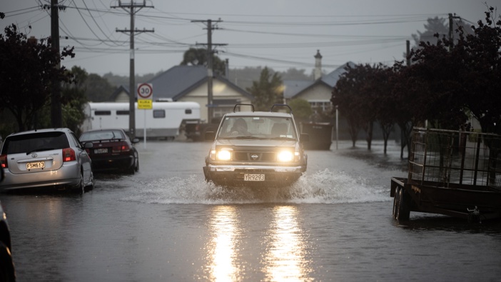 A car driving through the flooded streets in South Dunedin. Photo / George Heard