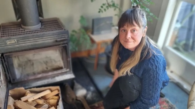 Rebecca James with the old woodburner that has been assessed as unsafe to use. Photo / RNZ