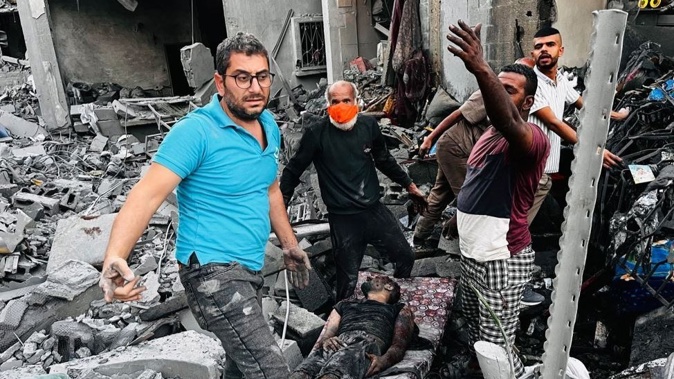 Palestinians help a wounded man at the site of an Israeli strike in Jabalia in the northern Gaza Strip on October 28. Photo / AFP