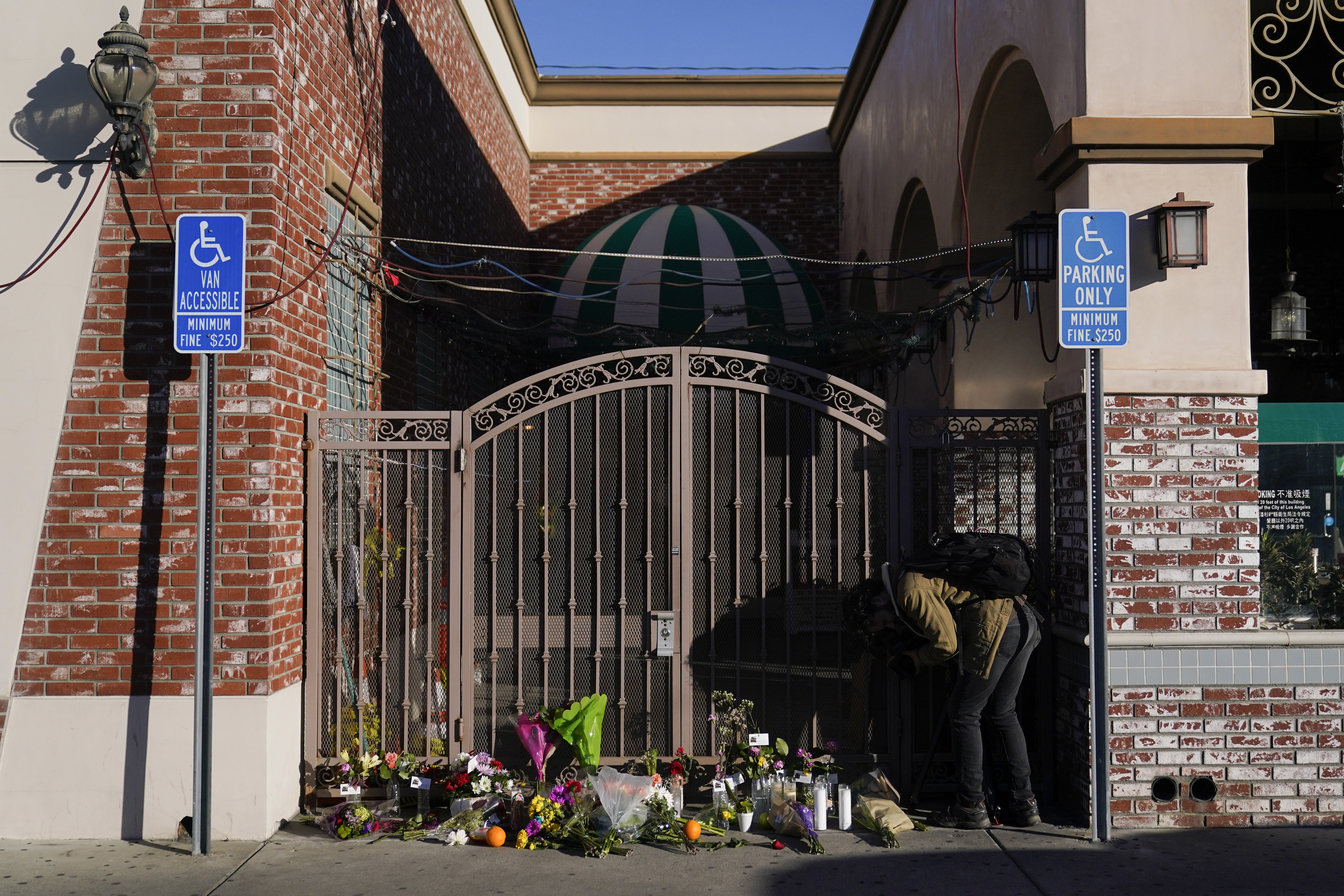 A videographer records flowers and candles placed outside Star Dance Studio in Monterey Park, Calif., Monday, Jan. 23, 2023. Photo / AP