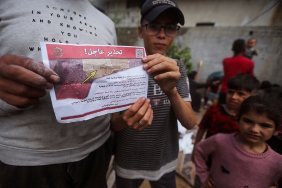 Palestinians hold leaflets dropped by Israeli planes calling on them to evacuate ahead of an Israeli military operation in Rafah, southern Gaza Strip on May 6. Photo / AP