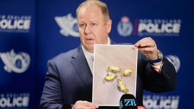 Detective Inspector Glenn Baldwin holds up a photo of the Rinda-branded meth-laced lollies found in food parcels given to needy families. Photo / Alex Burton