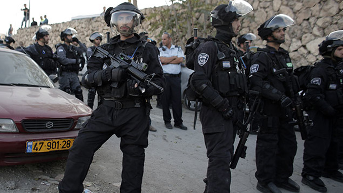 Members of the Israeli security forces stand guard while Palestinian demonstrate against new concrete blockades at the entrance of the flashpoint Arab village of Issawiya in East Jerusalem on November 12, 2014 (Getty)