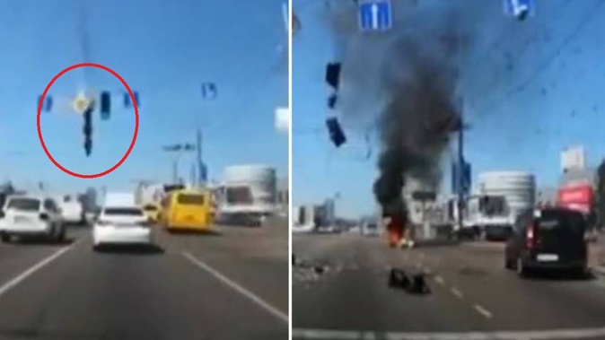 In the video, the missile drops down onto the middle of the road, narrowly missing two white cars. Photo / @AlexPanchenko2 / Twitter
