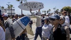 A demonstrator holding a bodyboard written in Spanish 'I don't want to die' protests the disappearance of foreign surfers in Ensenada, Mexico. Photo / AP