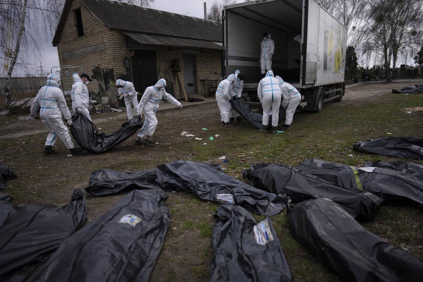 Volunteers load bodies of civilians killed in Bucha onto a truck to be taken to a morgue for investigation, in the outskirts of Kyiv, Ukraine. (Photo / AP)