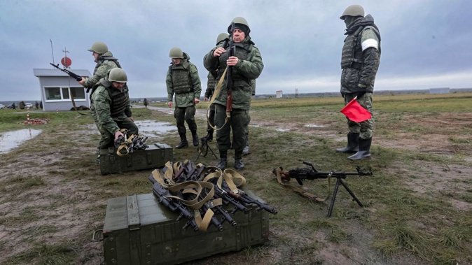 Recruits prepare their weapons as an instructor watches during military training at a firing range in Volgograd region, Russia last month. Photo / AP