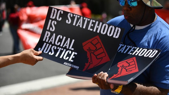 A demonstrator hands out signs demanding DC statehood during a protest in the District last year. Photo / Astrid Riecken, for The Washington Post