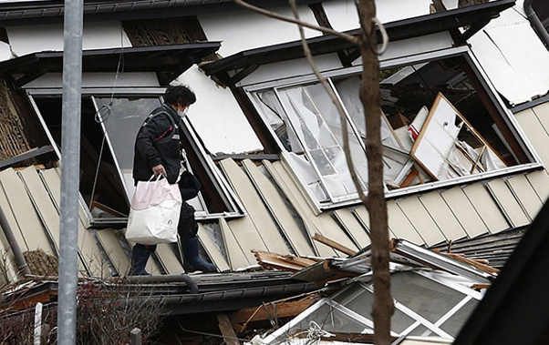 A local resident leaves after picking up her belongings from her collapsed house after a strong earthquake hit the area the night before, in Hakuba, some 300 kms northwest of Tokyo, Nagano prefecture, on November 23, 2014 (Getty)
