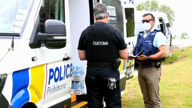 Detective Senior Sergeant Kevan Verry, of the Organised Crime Unit, speaks to a Customs officer outside an address on Takahiwai Rd in One Tree Point. (Photo / Tania Whyte)